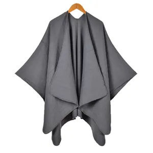 Deep grey cashmere-style knit poncho with side split and stitched edge on wooden hanger