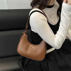 Brown woven texture underarm bag for women worn by a model in a minimalist setting