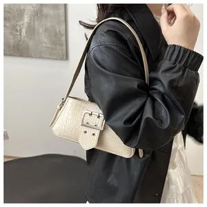 Detail view of cream crocodile texture shoulder bag with large silver metal buckle strap
