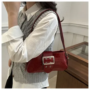 Detail of dark red croc-embossed underarm bag with a large silver buckle on a model