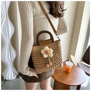 Detail of handmade woven straw bag featuring a 3D floral accent and wooden handle