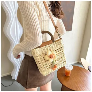 Detail of beige woven straw handbag with wooden handle and floral decoration