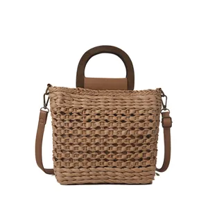 Handwoven straw tote bag with round wooden handles and adjustable brown shoulder strap