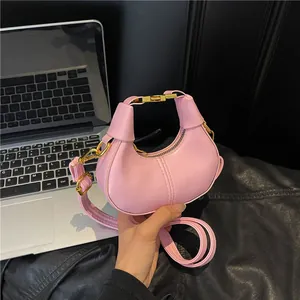 Pink faux leather half-moon mini bag with gold hardware and adjustable strap