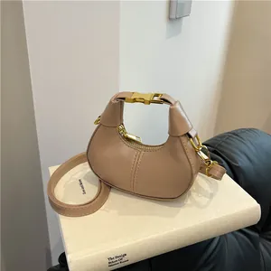 Minimalist beige dumpling bag with gold hardware on book background