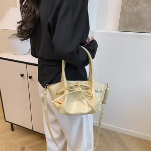 Fashionable beige bucket bag with bow detail and adjustable strap for women in lifestyle setting