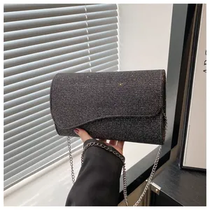 Close-up of glittery black evening clutch featuring a silver chain and curved flap
