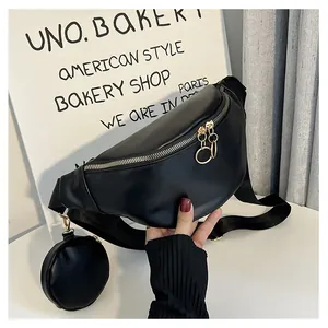 Détail du sac ceinture en similicuir noir avec boucles dorées et petite pochette ronde