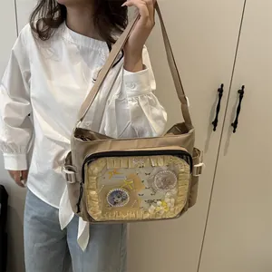 Khaki nylon crossbody ita bag with transparent window and lace trim on a female model