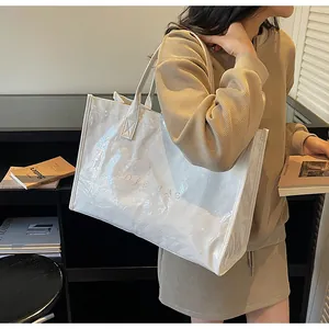 Glossy white tote bag with textured crinkle finish and embossed letters in model setting