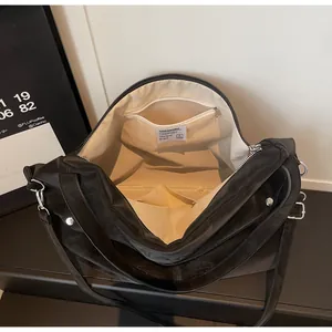 Detail view of large black crossbody bag showing internal zipper pocket and fabric lining