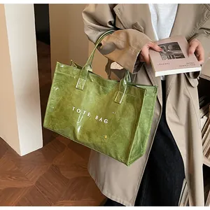 Detailed view of olive green tote bag featuring high-gloss texture and bold white lettering
