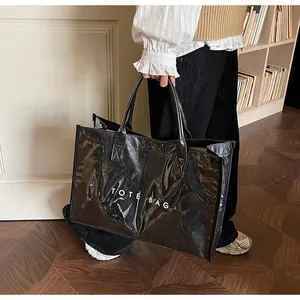 Detail showing high-gloss black tote bag texture and white printed TOTE BAG text