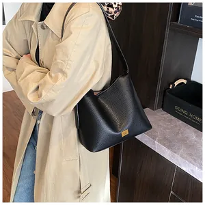 Détail du sac cabas en cuir grainé noir avec plaque logo dorée élégante