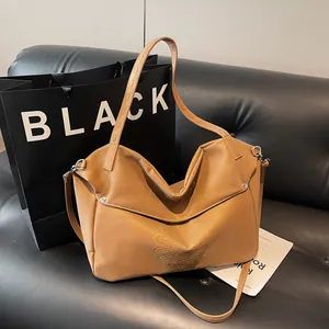Brown faux leather large tote bag with embossed daisy pattern on black sofa