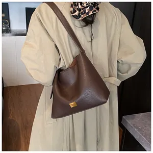 Détail du sac en cuir marron grainé avec une plaque logo KOSH MBR en métal doré
