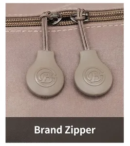 Macro view of high-quality dual metal zippers with GB logo on a beige travel bag