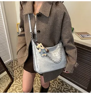Détail du sac cabas croissant argenté avec chaîne et breloque ours sur le mannequin