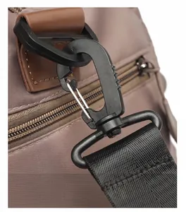 Detail of thickened black swivel buckle and nylon strap on a brown travel bag