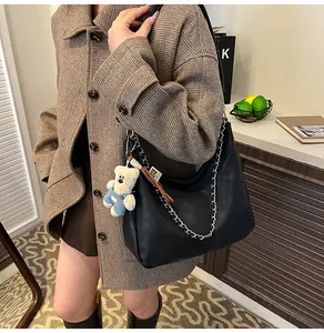 Détail du sac hobo noir avec une grosse chaîne argentée et un charm ours en peluche