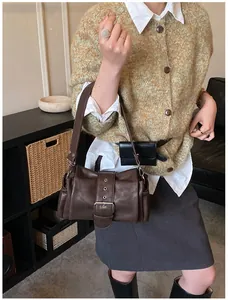 Close-up of the vintage brown shoulder bag showing its matte leather texture and large buckle