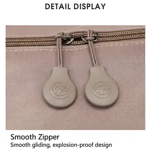 Detail view of the smooth dual zippers with circular B-logo pulls on a brown travel bag