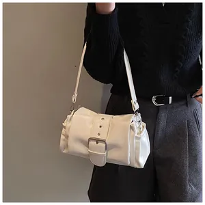 Detail view of a creamy white underarm bag featuring a wide decorative buckle and soft PU leather