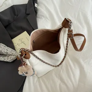 Sac cabas blanc en demi-lune avec chaîne et charme ours sur un fond minimaliste chic