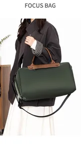 Detail of dark green travel bag featuring brown leather flap and adjustable shoulder strap