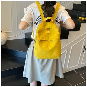 Dettaglio dello zaino in nylon giallo con tasche a zip e logo M sulla parte anteriore