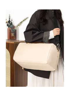 Detail of beige travel bag showing leather flap handle and black nylon shoulder strap
