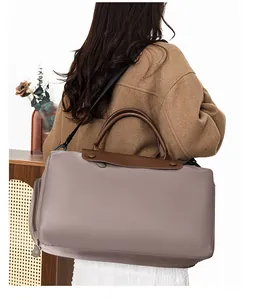 Detail of a large capacity travel tote bag with brown leather handles and nylon strap