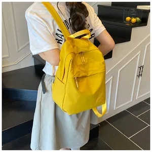 Dettaglio di uno zaino in nylon giallo brillante con logo M circolare sulla tasca frontale