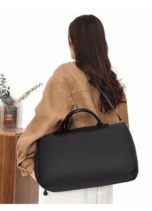 Detail of a large black travel tote bag with padded handles and adjustable shoulder strap