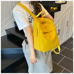 Dettaglio dello zaino in nylon giallo con logo M a rilievo e cerniera resistente