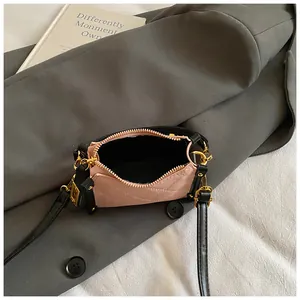Detail shot of a pink quilted crossbody bag with golden hardware on grey blazer background