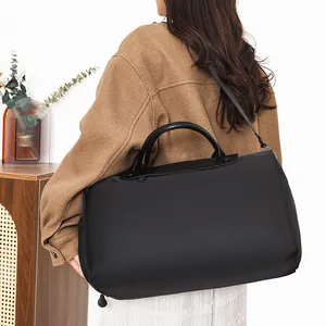 Large black minimalist travel bag with leather handles and adjustable strap on model