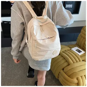 Dettaglio di uno zaino minimalista color crema ad alta capacità indossato da una modella