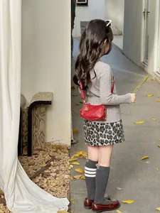 Close-up of a small red quilted faux leather crossbody bag for children with gold lock