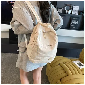 Dettaglio dello zaino in nylon crema che mostra la trama impermeabile e le zip