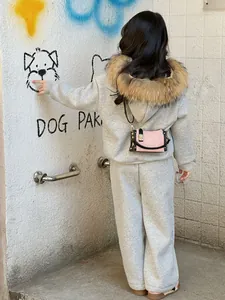Outdoor back view of a grey kids' hoodie set with faux fur trim and pink mini crossbody bag