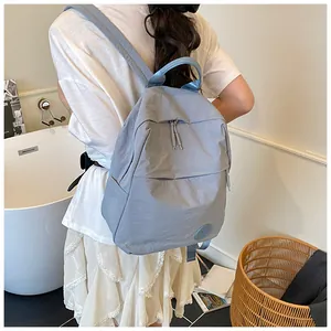 Vista posteriore di una modella con zaino in nylon blu-grigio con multitasche