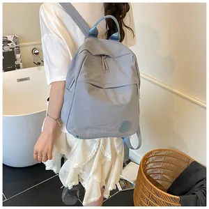 Dettaglio dello zaino in nylon azzurro con logo M rotondo e doppie cerniere per studenti