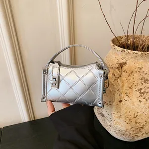 Silver quilted mini handbag with stud details and metal turn-lock shown in hand