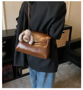Detail of vintage brown leather handbag with metallic turn-lock and plush bunny charm