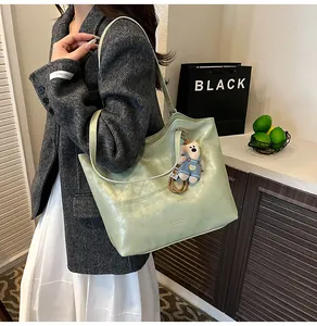 Detail of light green leather tote bag with cute bear charm and fashion text print