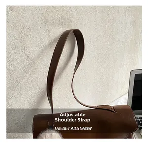 Detail of deep brown leather bag featuring precise stitching and adjustable shoulder strap