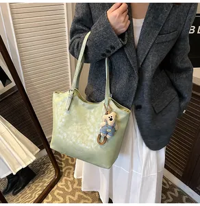 Detail of mint green tote bag featuring a cute plush bear pendant and textured material