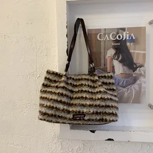 Close-up of plush striped tote bag featuring faux fur texture and leather straps