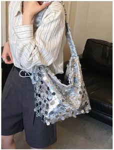 Detail of silver sequin tote bag with ruffled velvet handle shown on a model